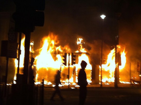LONDON, ENGLAND - AUGUST 06:  A Carpetright store burns on Tottenham High Road after being set on fire by youths protesting against the killing of a man by armed police in an attempted arrest, August 6, 2011 in London, England. Twenty-nine-year-old father-of-four Mark Duggan died August 4 after being shot by police in Tottenham, north London.  (Photo by Matthew Lloyd/Getty Images)